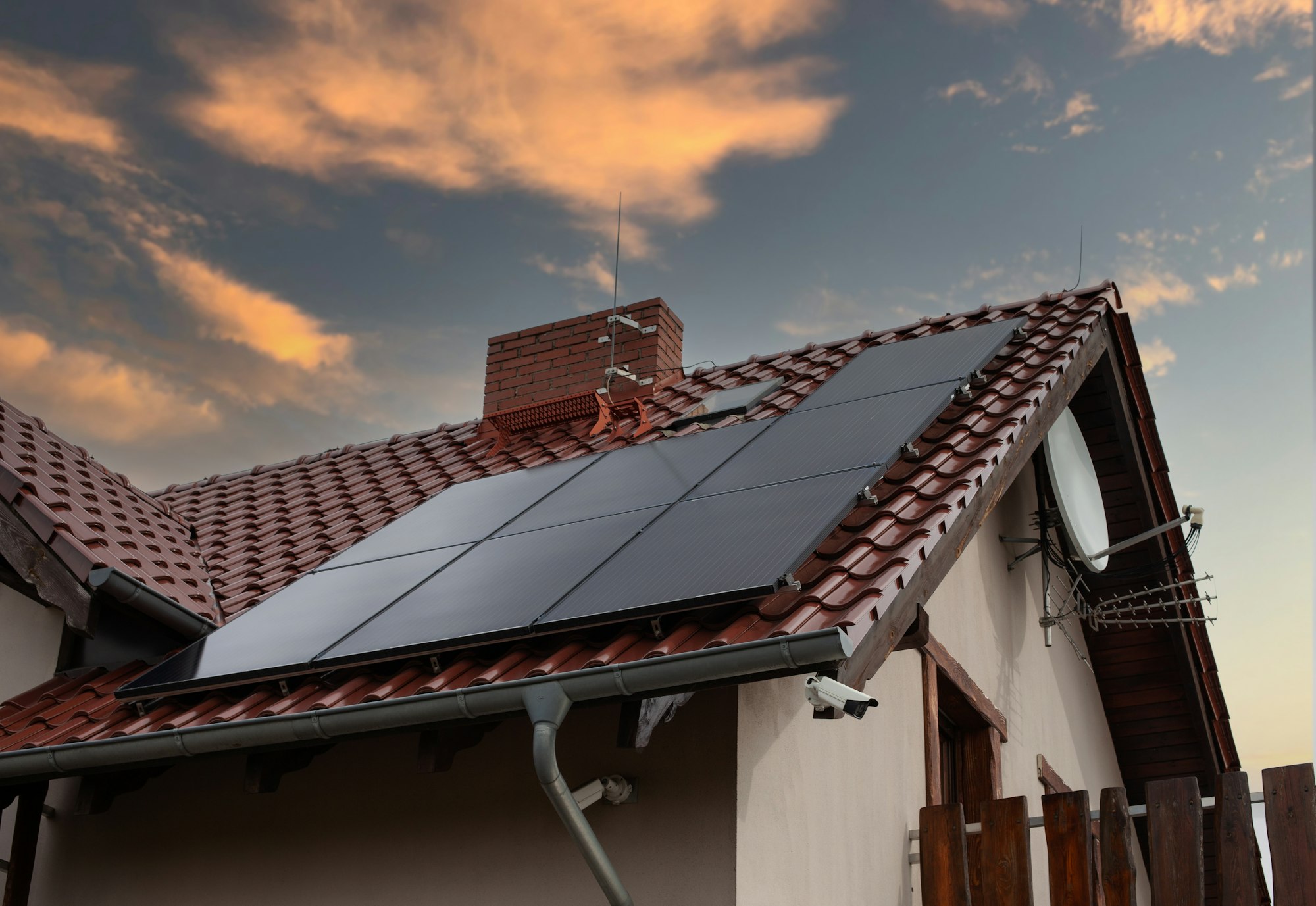 Low angle shot of a house with solar panels on the roof under a sunset sky